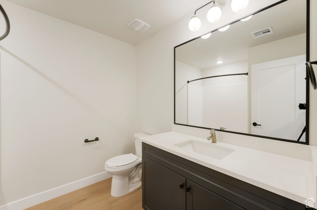 Bathroom featuring visible vents, toilet, baseboards, and wood finished floors