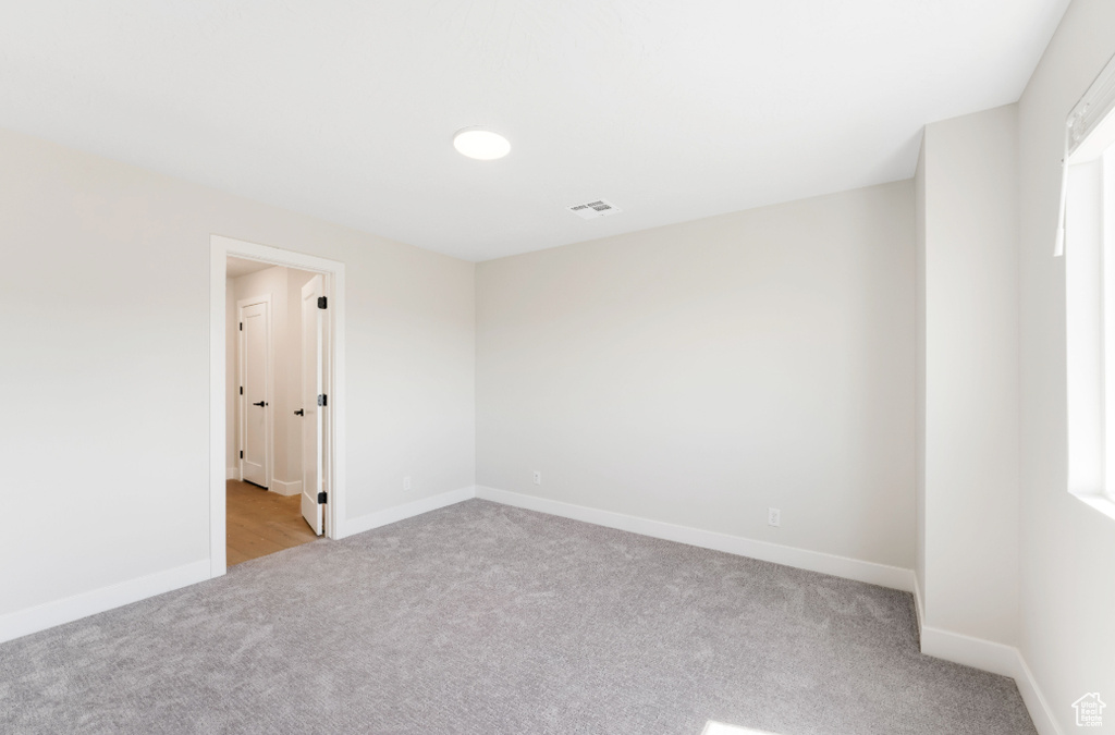 Unfurnished room featuring baseboards, visible vents, and light carpet