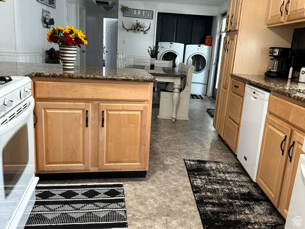 Kitchen with white appliances, washer and clothes dryer, light brown cabinets, and a peninsula