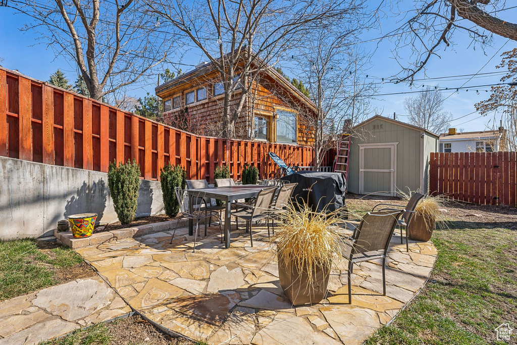 View of patio featuring an outbuilding, a shed, outdoor dining space, and a fenced backyard