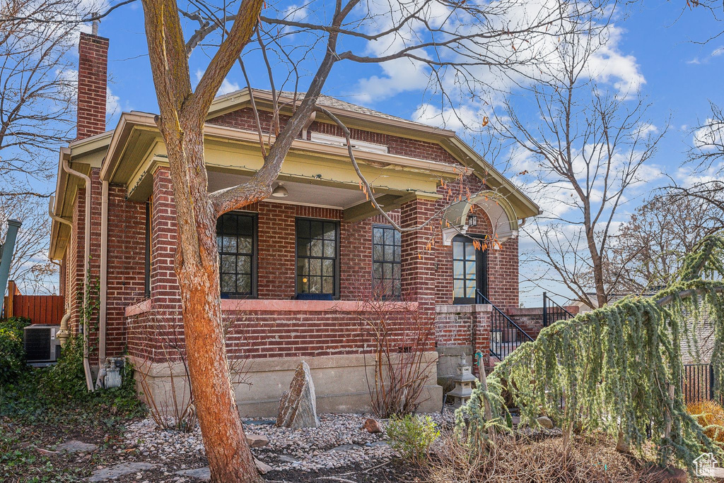 View of home's exterior featuring brick siding, central AC unit, a chimney, and fence