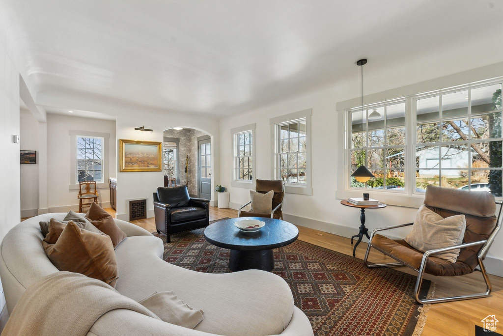 Living room with arched walkways, visible vents, baseboards, and wood finished floors