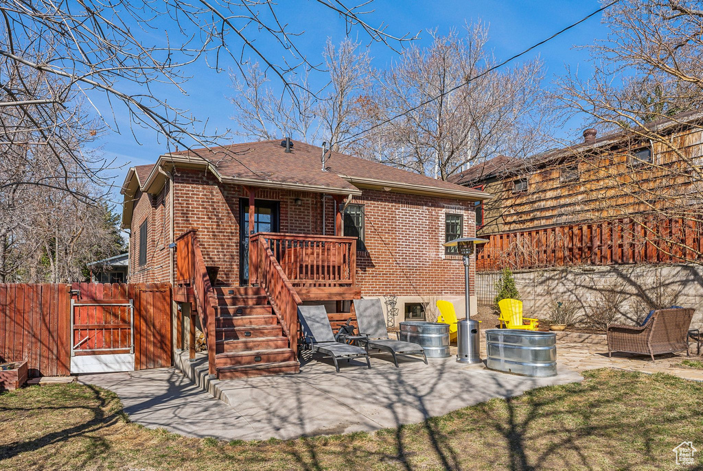 Back of property featuring a patio area, fence, brick siding, and a gate