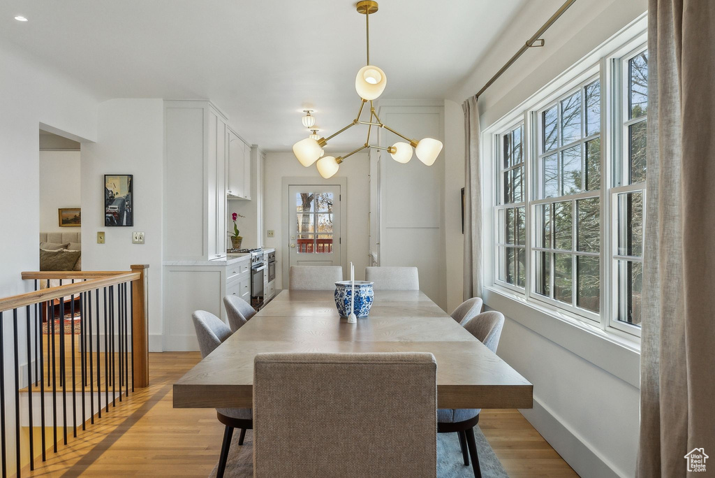 Dining space with baseboards, a notable chandelier, and light wood finished floors