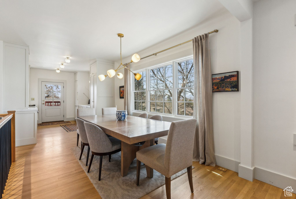 Dining room featuring light wood-style floors, baseboards, and a chandelier