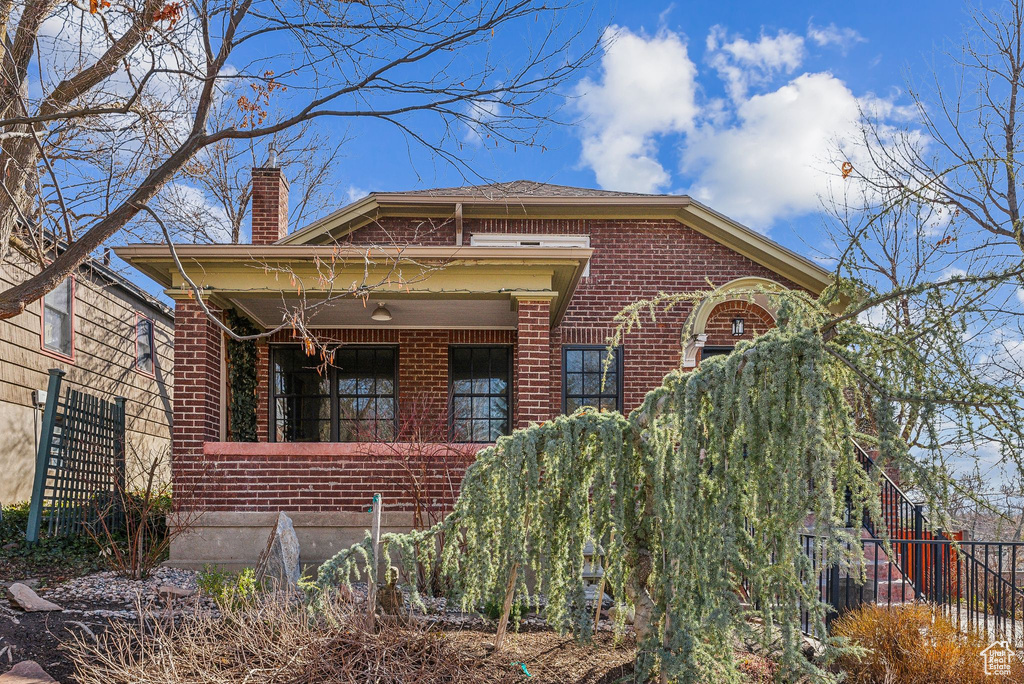 View of property exterior with brick siding, a chimney, and fence