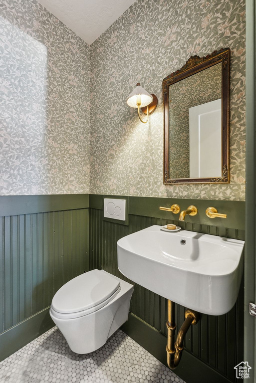 Bathroom with tile patterned floors, a wainscoted wall, and wallpapered walls
