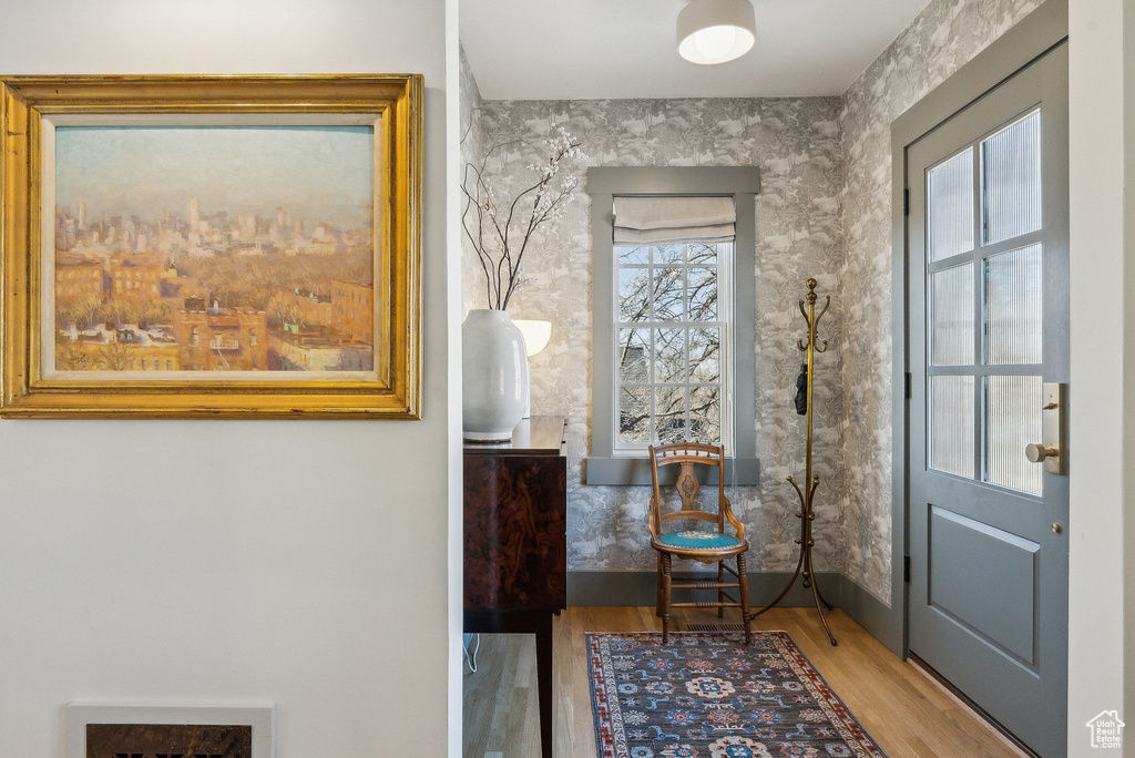 Foyer with wallpapered walls, baseboards, and wood finished floors