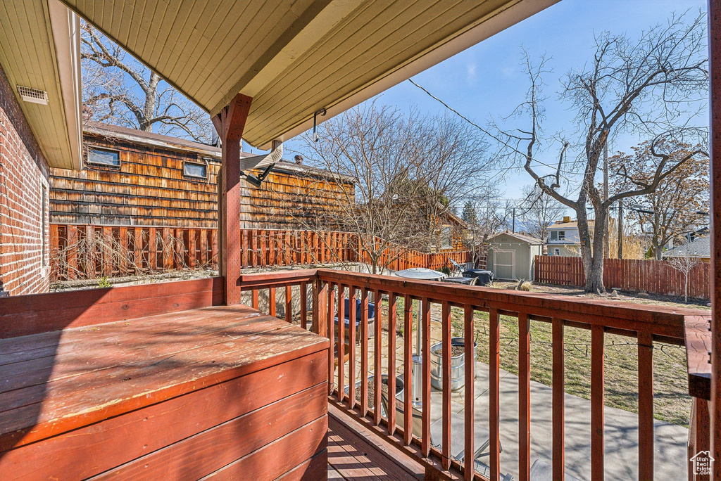 Wooden deck featuring a fenced backyard, a shed, and an outdoor structure