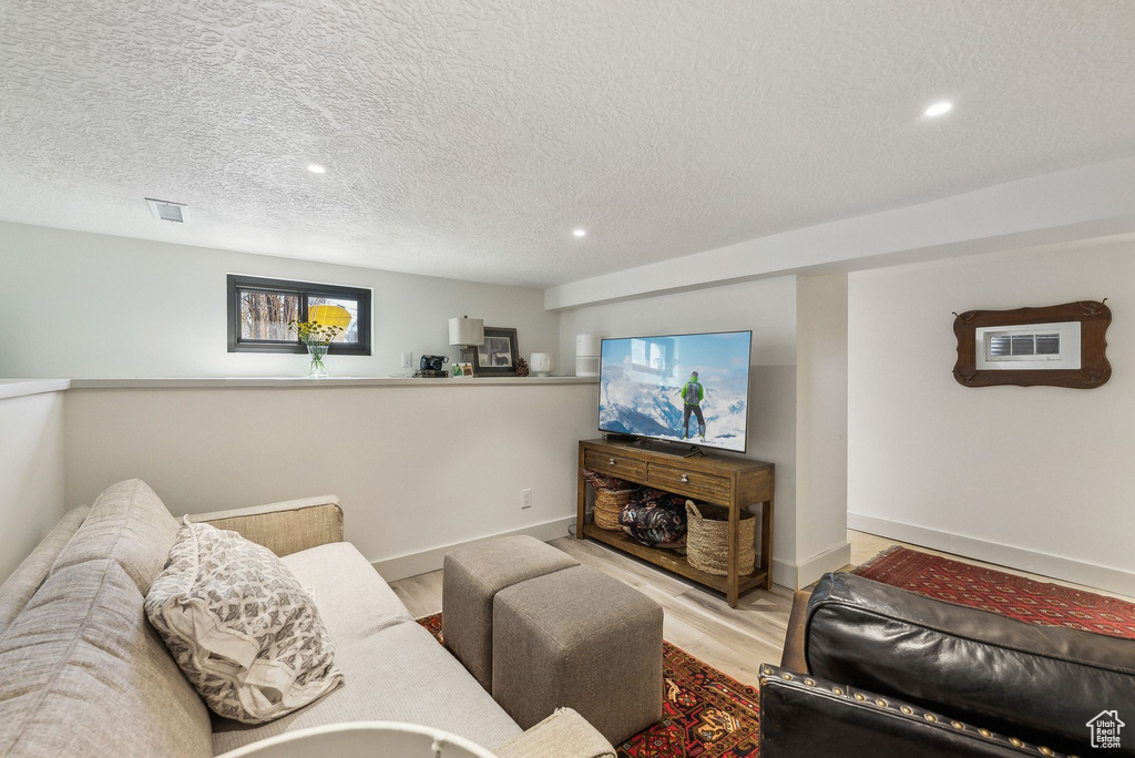 Living area featuring a textured ceiling, baseboards, visible vents, and light wood-type flooring