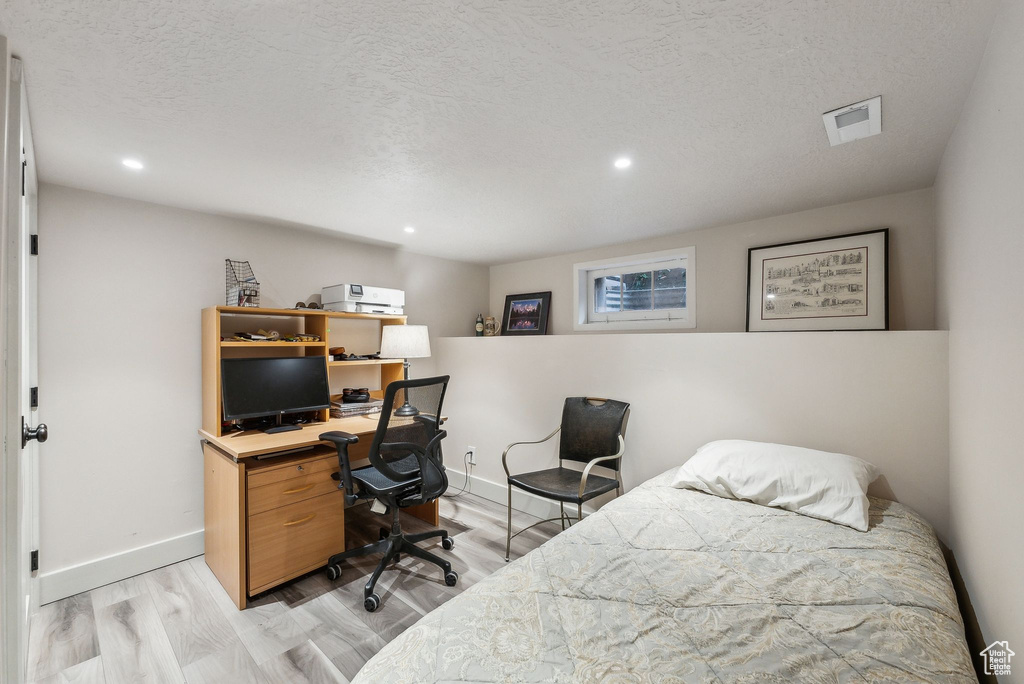Bedroom with visible vents, a textured ceiling, light wood-type flooring, and baseboards