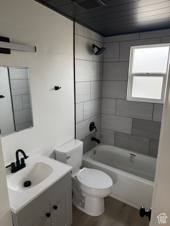 Bathroom featuring shower / bath combination, visible vents, wood finished floors, vanity, and toilet