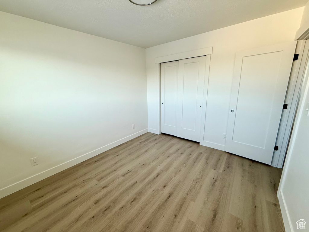 Unfurnished bedroom with a closet, baseboards, and light wood finished floors
