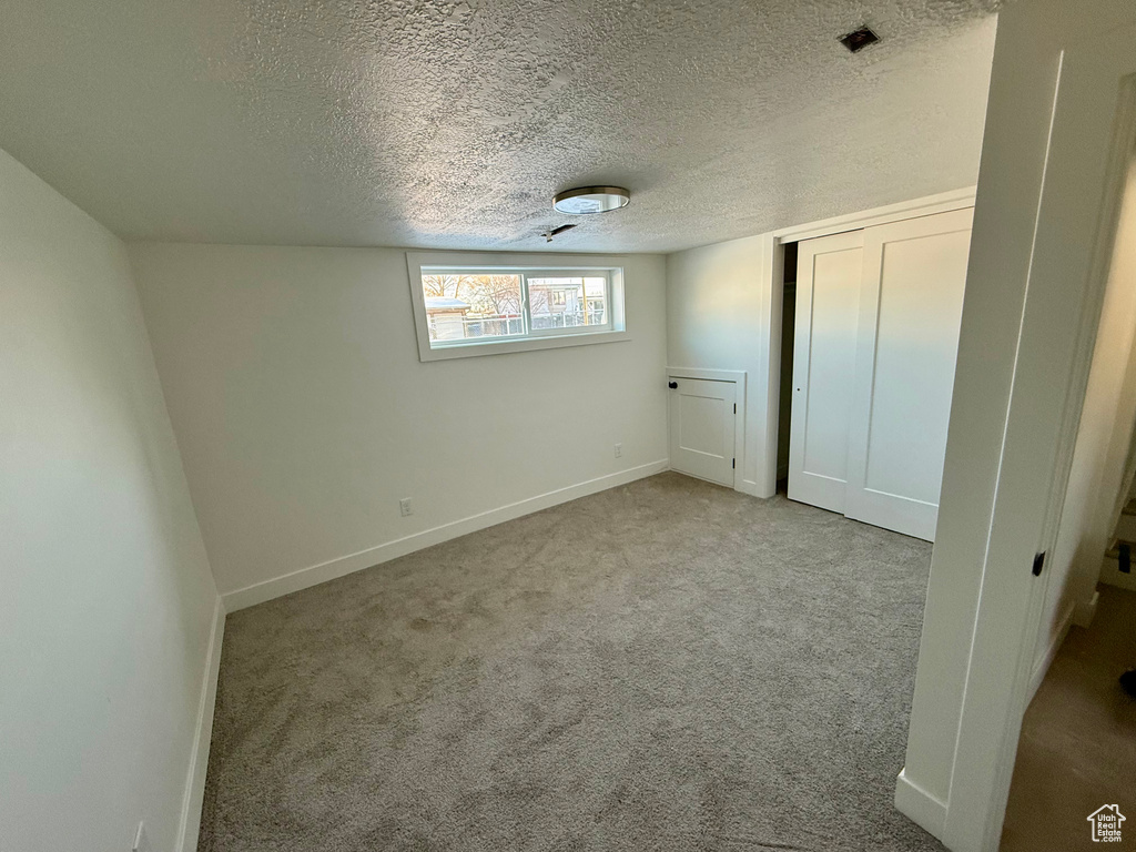 Unfurnished bedroom featuring carpet flooring, baseboards, a closet, and a textured ceiling