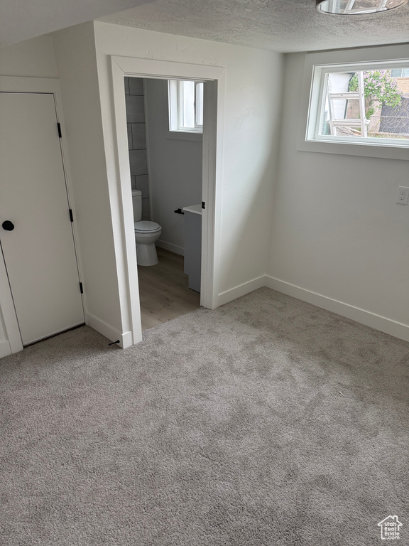 Unfurnished bedroom featuring carpet floors, baseboards, a textured ceiling, and connected bathroom
