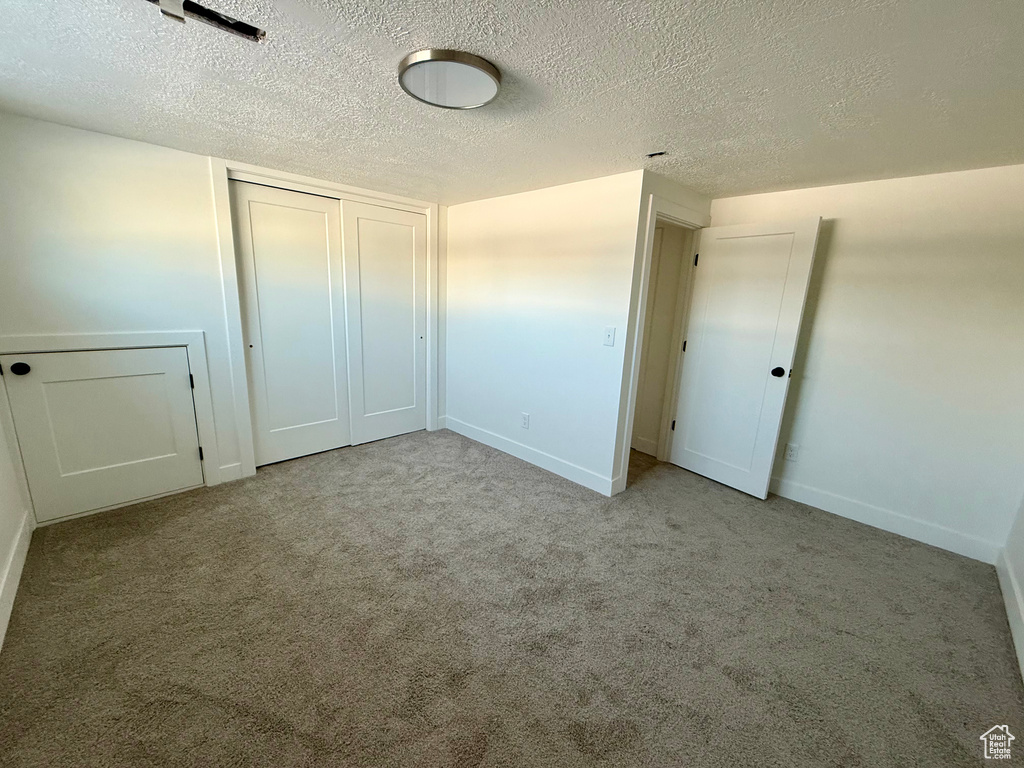 Unfurnished bedroom featuring a closet, baseboards, carpet, and a textured ceiling