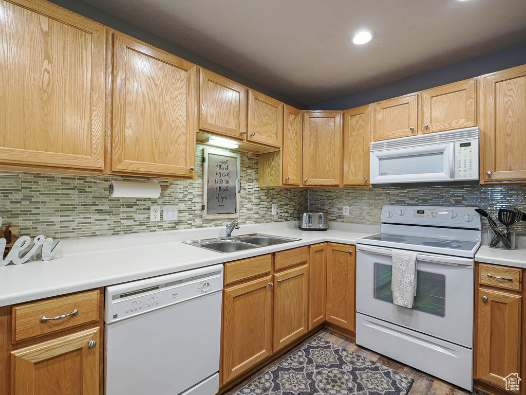 Kitchen with white appliances, tasteful backsplash, a sink, and light countertops