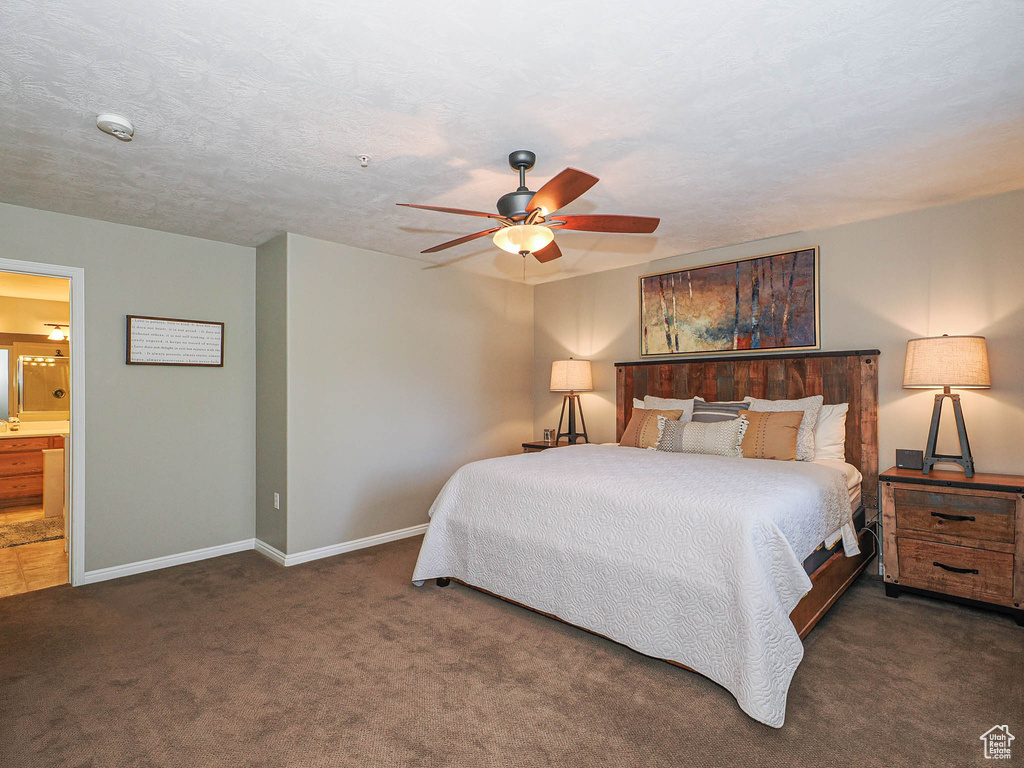 Carpeted bedroom featuring baseboards, a ceiling fan, and ensuite bathroom