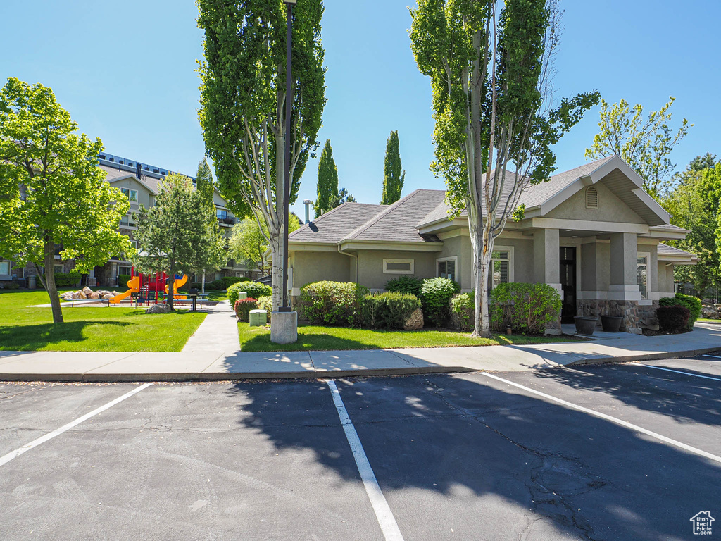 View of front of house with a front lawn, uncovered parking, stone siding, stucco siding, and playground community
