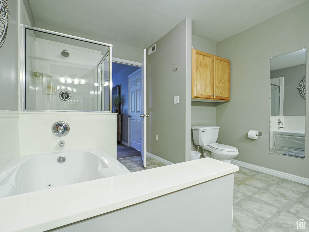 Bathroom featuring visible vents, toilet, a tub with jets, baseboards, and an enclosed shower