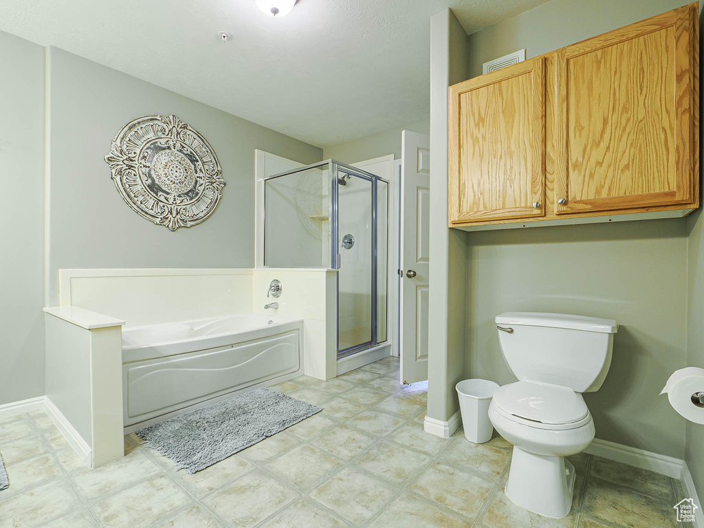 Full bathroom featuring toilet, baseboards, a shower stall, visible vents, and a bath