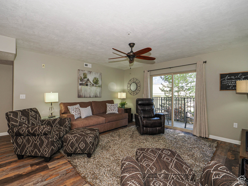 Living room featuring wood finished floors, baseboards, ceiling fan, and a textured ceiling