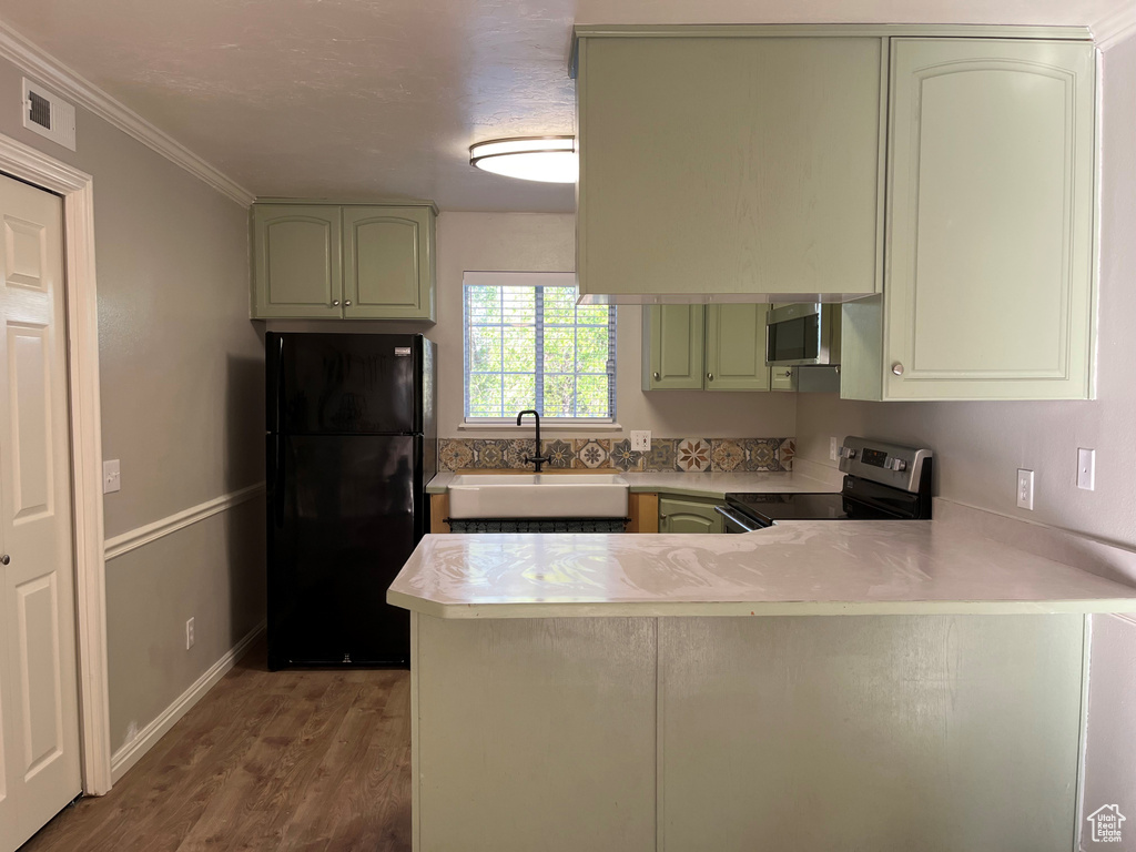 Kitchen with light wood finished floors, a peninsula, a sink, light countertops, and appliances with stainless steel finishes