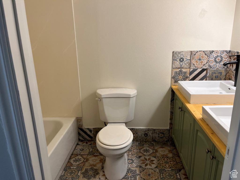 Full bathroom featuring a bathtub, tile patterned flooring, toilet, and vanity