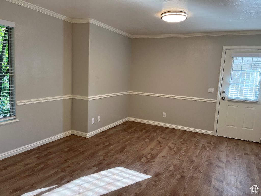 Empty room featuring baseboards, wood finished floors, and crown molding