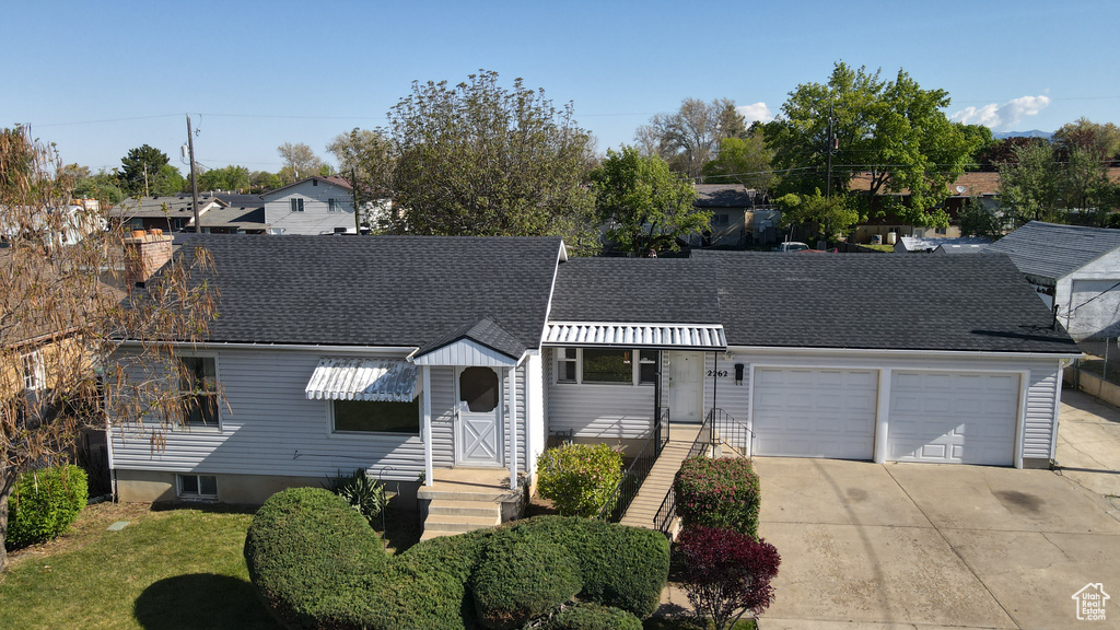 View of front of property featuring driveway, a front yard, roof with shingles, a residential view, and an attached garage