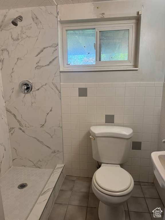 Bathroom with wainscoting, toilet, tile walls, walk in shower, and tile patterned floors