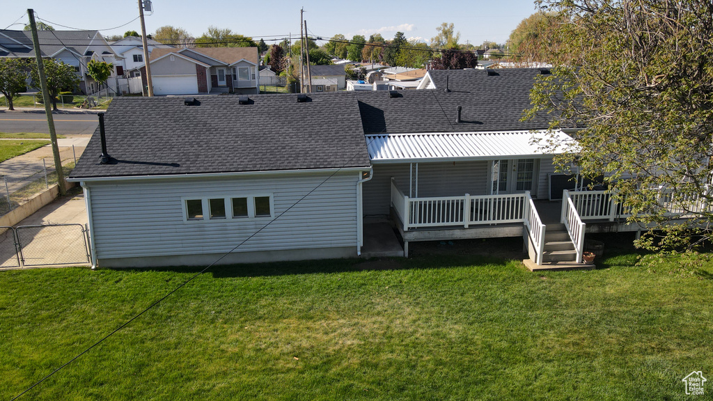 Back of property with roof with shingles, a yard, a residential view, and a deck