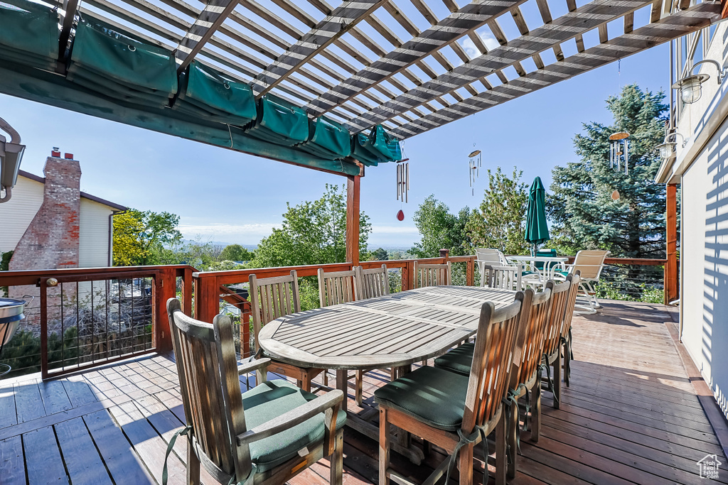 Wooden terrace featuring outdoor dining area and a pergola
