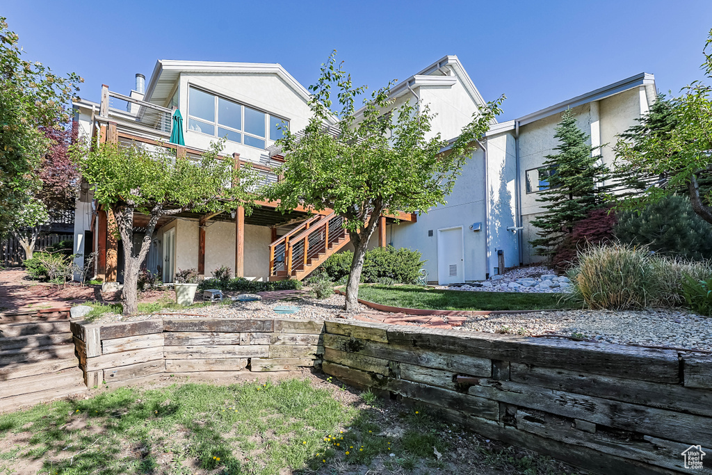 View of front of property featuring stairway, a wooden deck, and stucco siding