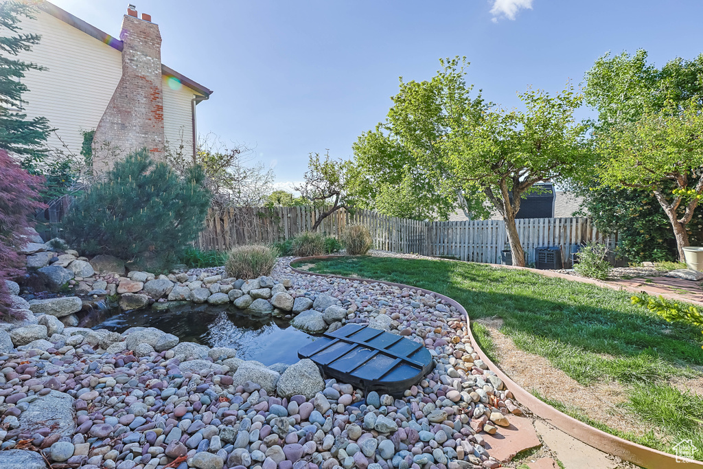 View of yard with a small pond, cooling unit, and a fenced backyard