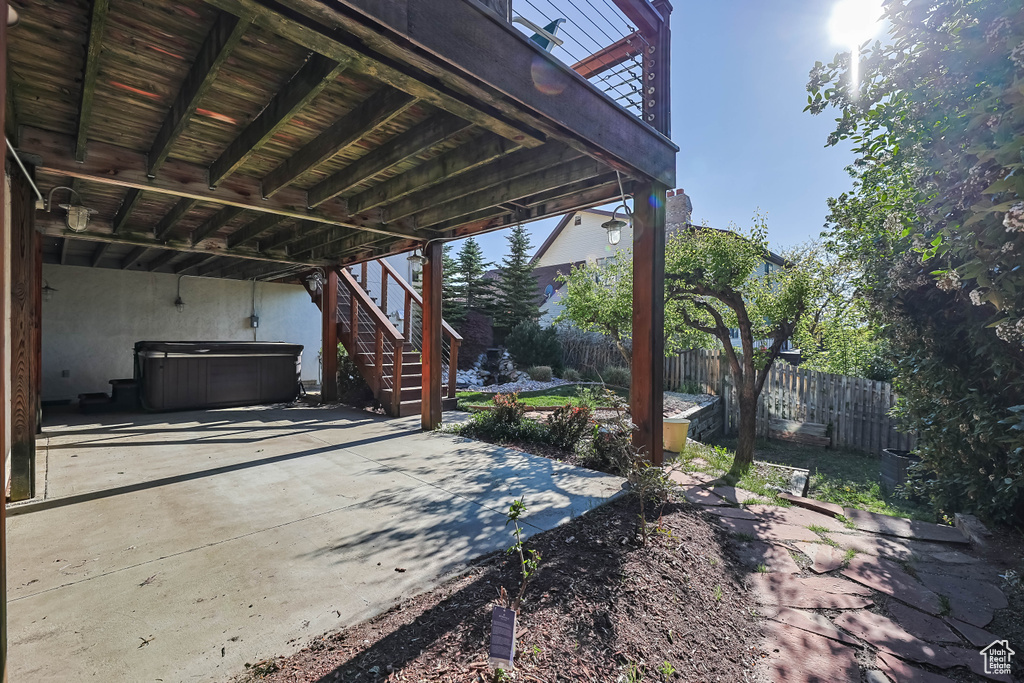 View of patio with fence, stairs, and a hot tub