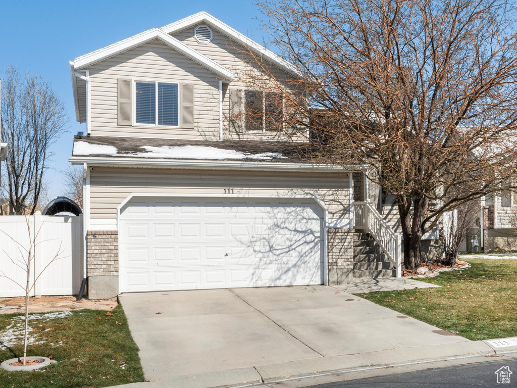 View of front of house featuring driveway, a gate, fence, a front yard, and a garage