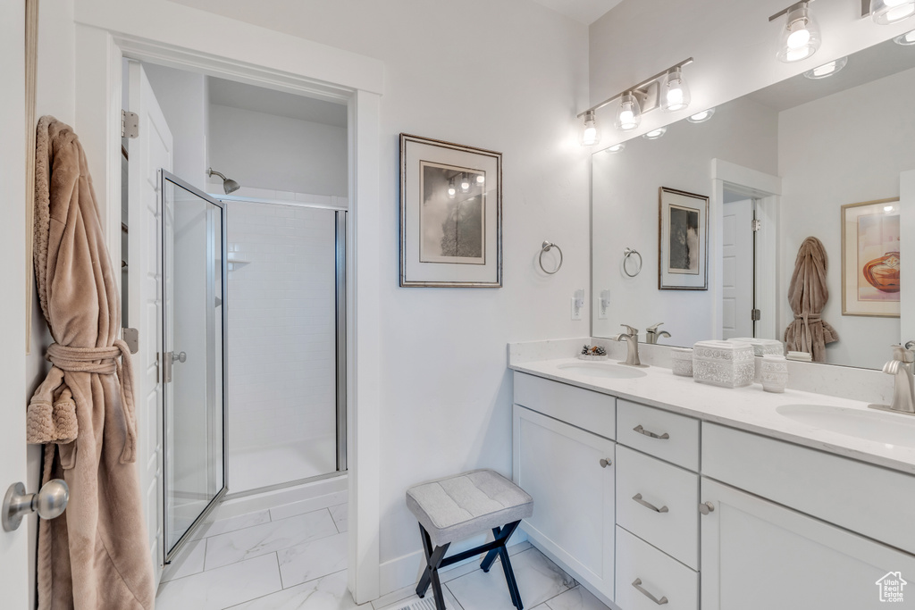 Full bath featuring double vanity, marble finish floor, a shower stall, and a sink