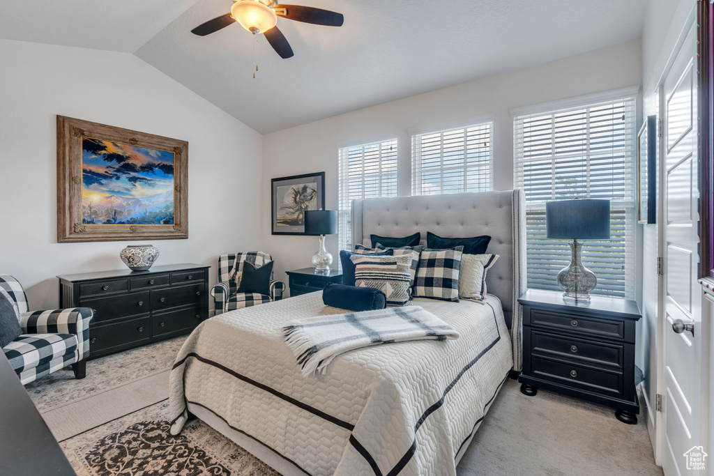 Bedroom featuring light carpet, multiple windows, lofted ceiling, and ceiling fan
