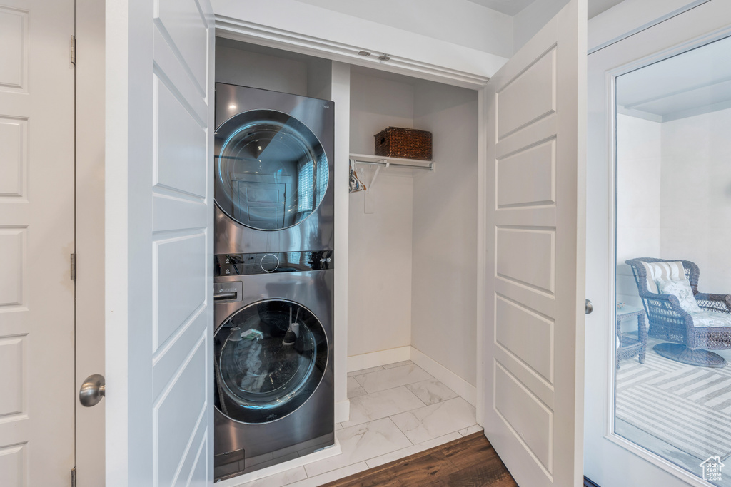 Laundry area featuring laundry area, marble finish floor, stacked washer and clothes dryer, and baseboards
