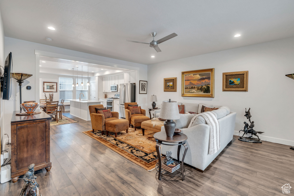 Living room with recessed lighting, wood finished floors, baseboards, and ceiling fan
