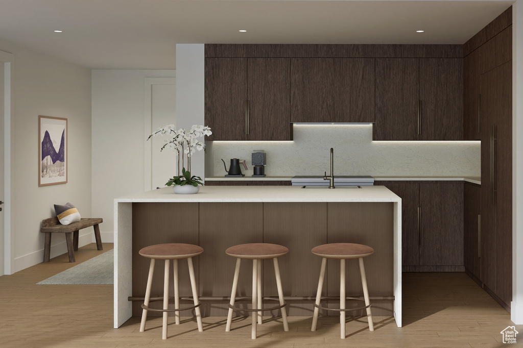 Kitchen with dark brown cabinets, a breakfast bar area, light countertops, and a sink