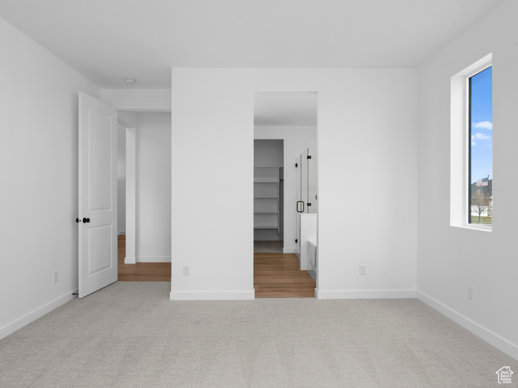 Unfurnished bedroom featuring carpet flooring, a walk in closet, and baseboards
