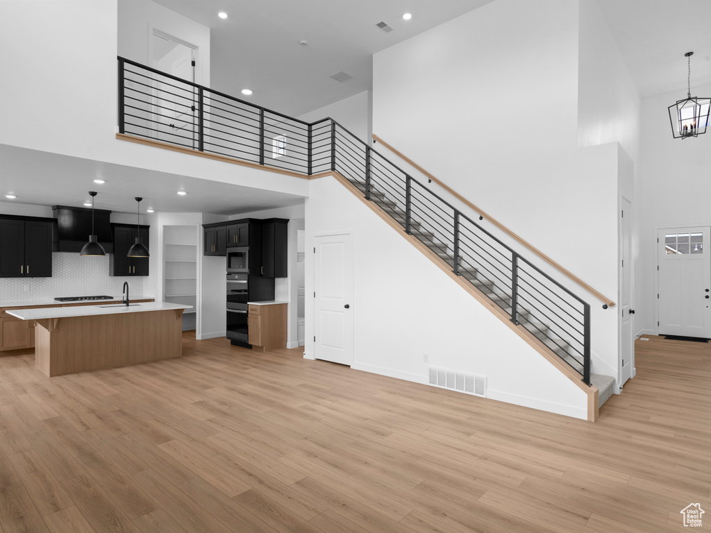 Kitchen featuring stainless steel microwave, light wood finished floors, visible vents, and a towering ceiling