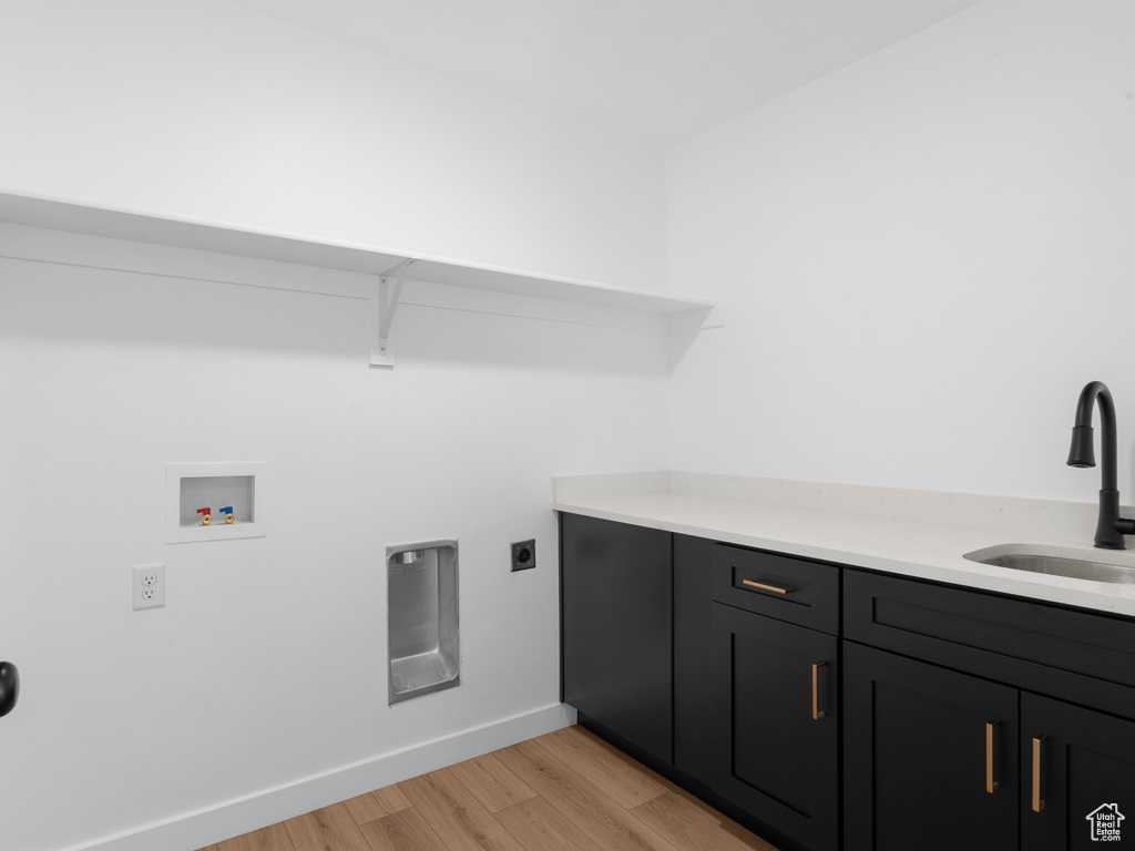 Washroom featuring light wood-type flooring, hookup for a washing machine, cabinet space, electric dryer hookup, and a sink