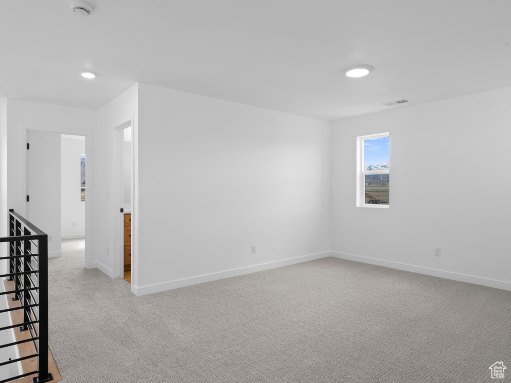 Unfurnished room featuring light colored carpet, visible vents, and baseboards