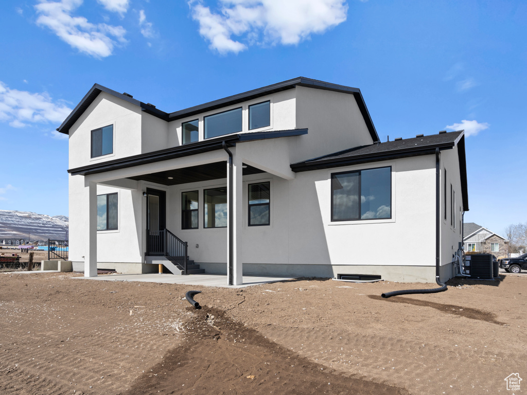 Rear view of house featuring stucco siding and cooling unit