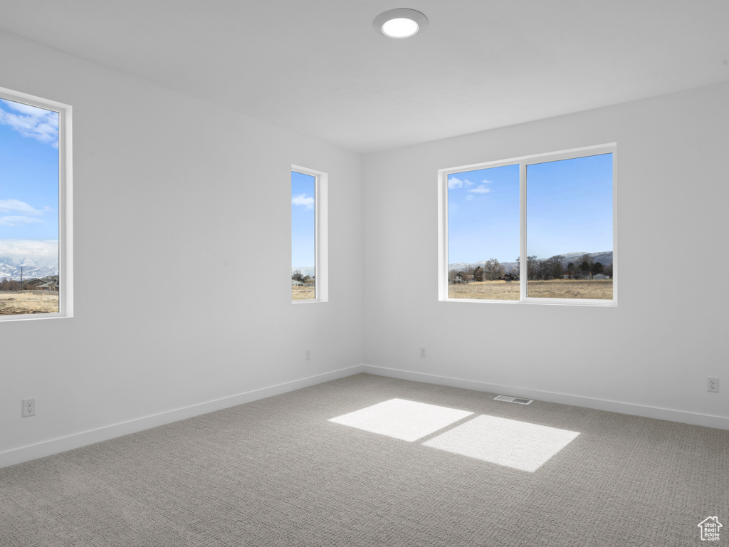 Spare room featuring visible vents, baseboards, and carpet