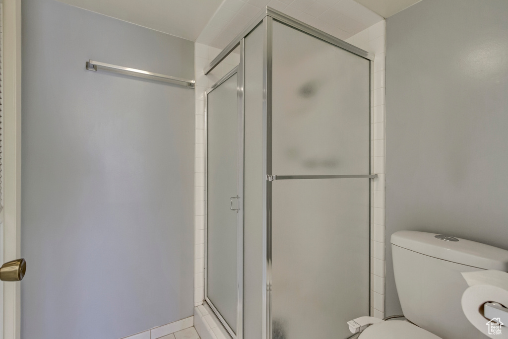 Full bathroom with tile patterned floors, a shower stall, and toilet