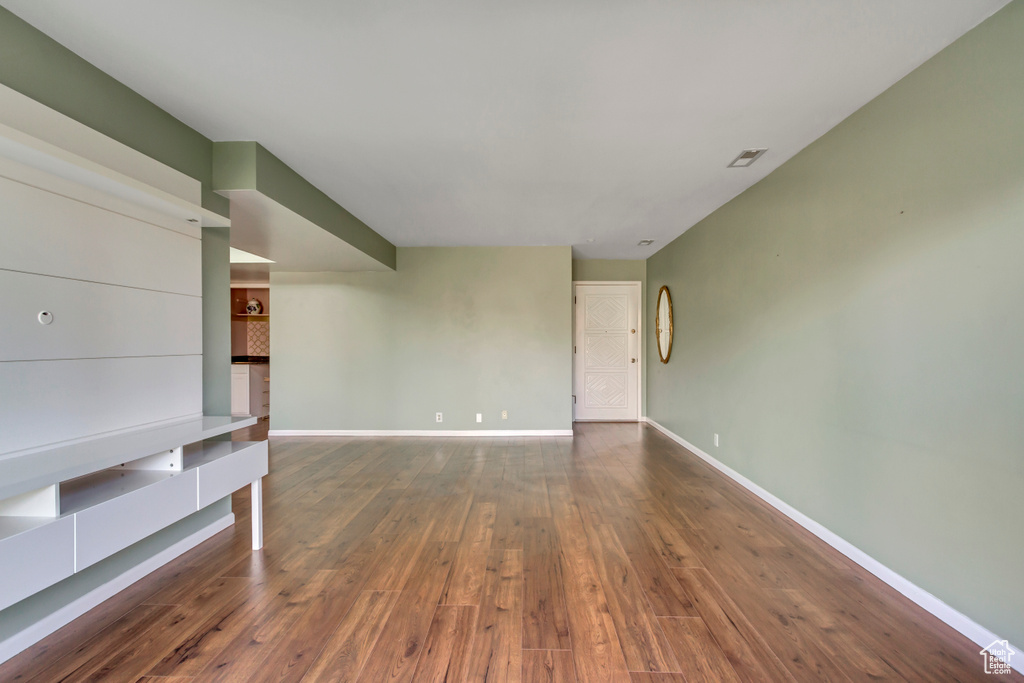 Unfurnished living room featuring baseboards, wood-type flooring, and visible vents
